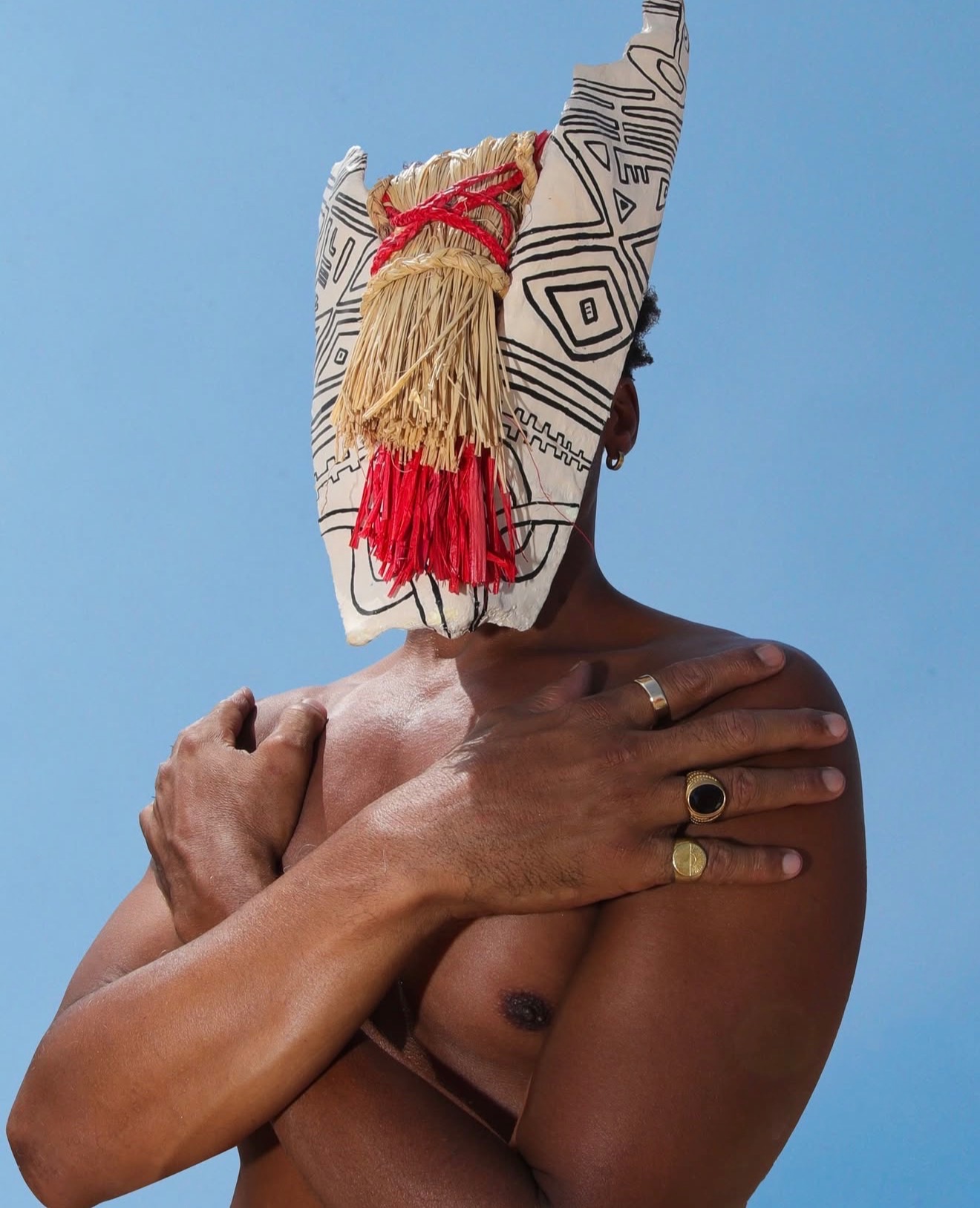 Personne portant un masque sculptural devant un ciel bleu